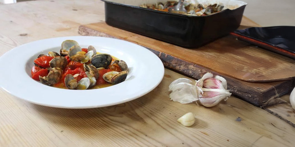 Clams and tomatoes in a bowl on a wooden table